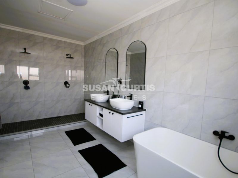 Modern bathroom featuring a double vanity with vessel sinks, a spacious walk-in shower, and a contemporary freestanding bathtub with high-quality tiled finishes.
