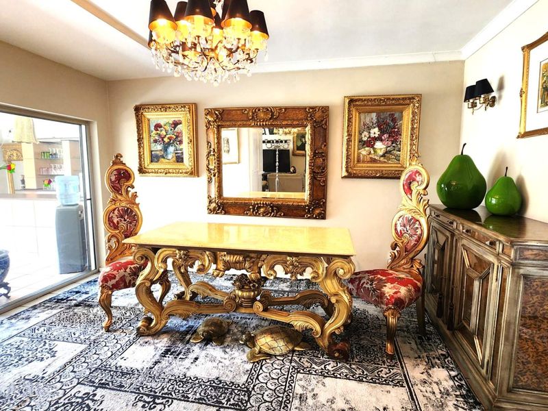 Elegant dining room featuring a crystal chandelier, decorative cove ceiling, and large sliding glass doors providing access to the outdoor area.