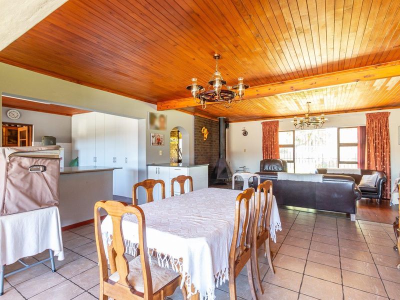 Spacious open-plan living and dining area featuring a warm timber ceiling, tiled floors, and a cozy freestanding fireplace.
