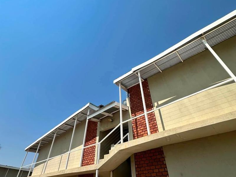 Exterior view of an apartment building featuring exposed brick accents, metal staircases, and balcony walkways under a clear sky.