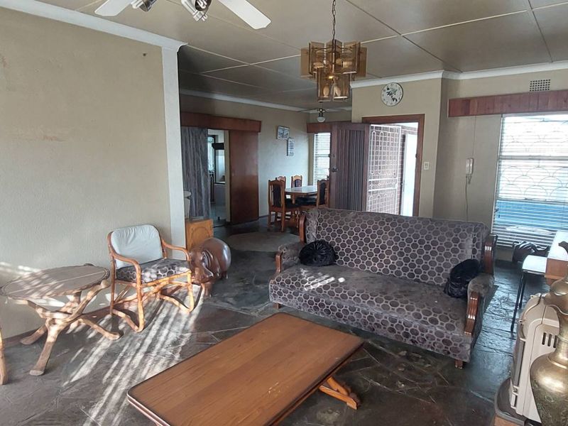 Spacious living area featuring natural stone flooring, a prominent brick fireplace, and direct access to the dining space.