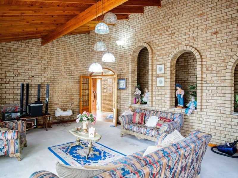Spacious living room featuring exposed timber ceiling beams, distinctive face brick walls, and decorative arched wall niches.
