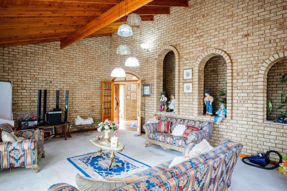 Spacious living room featuring exposed timber ceiling beams, distinctive face brick walls, and decorative arched wall niches.
