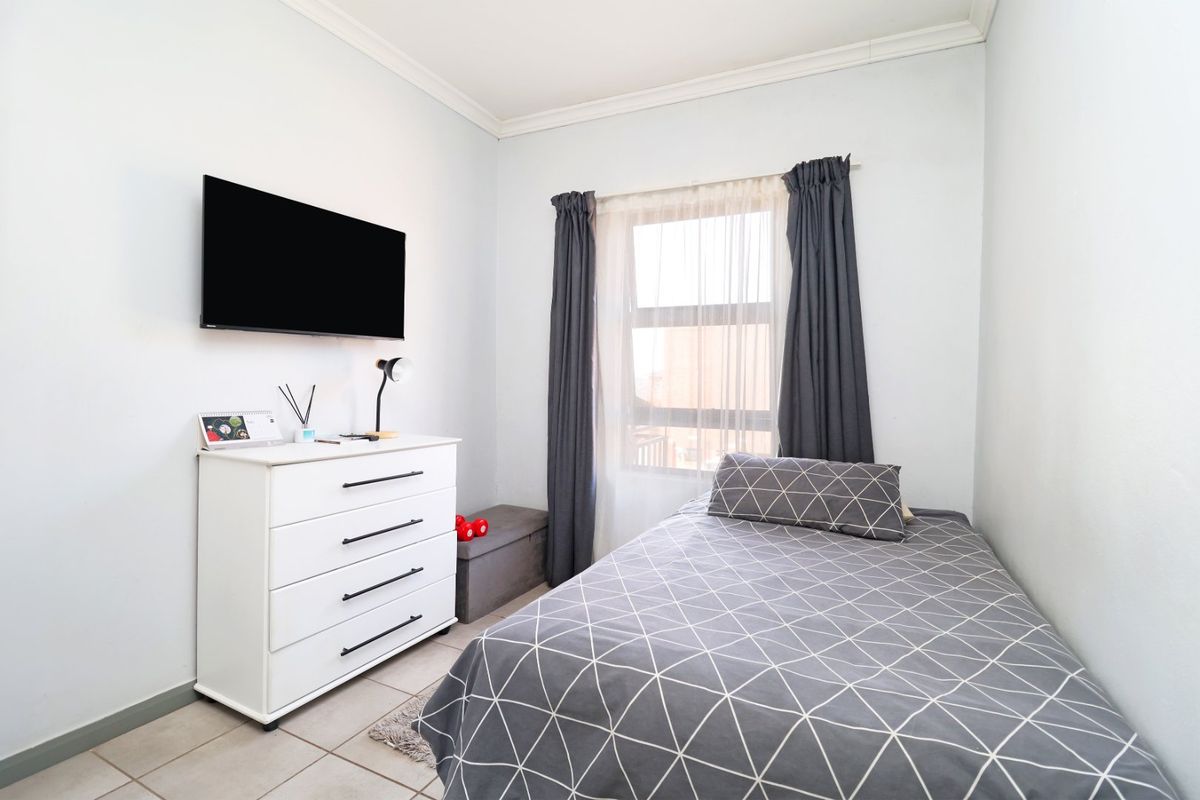 A well-maintained bedroom featuring tiled flooring, neutral wall finishes, and classic cornicing, providing a clean and functional living space.
