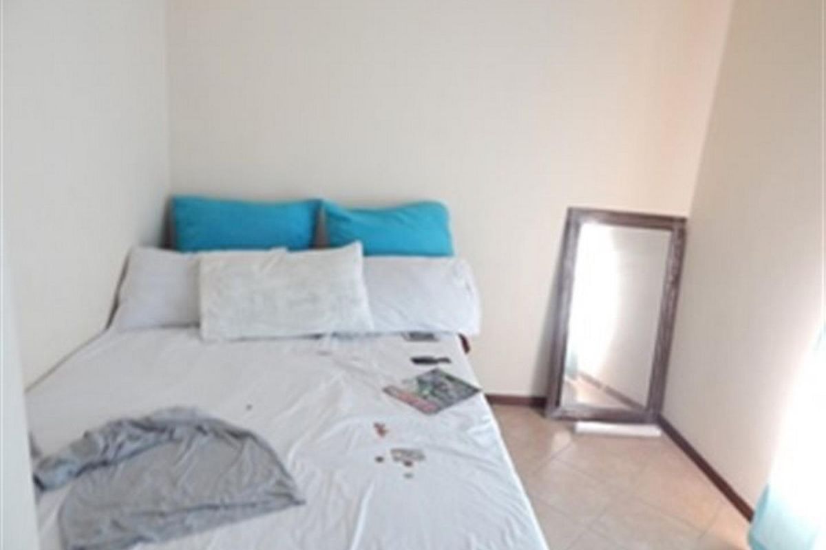 A compact bedroom featuring tiled flooring and neutral wall finishes, providing a functional space for rest.