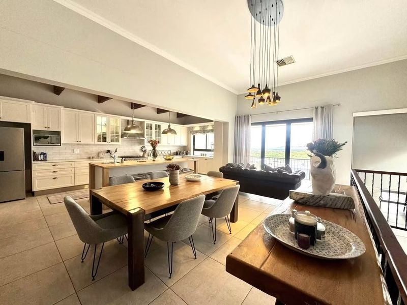 Spacious open-plan living and dining area featuring a modern kitchen with island, tiled floors, and large sliding doors leading to a balcony with views.