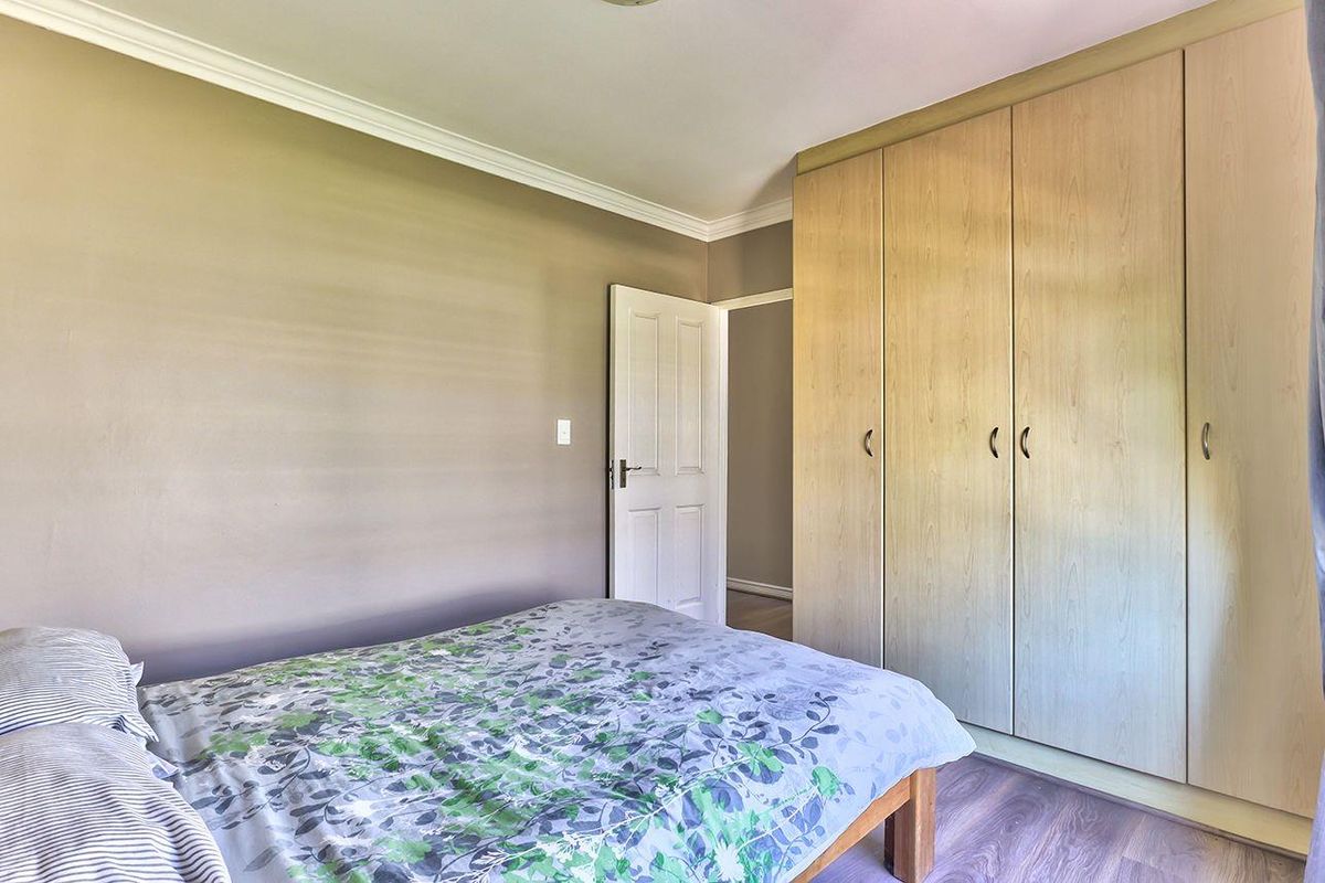 A bedroom featuring laminate flooring, neutral wall tones, and ample built-in cupboard storage space.