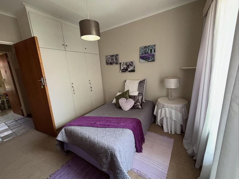 A functional bedroom featuring built-in cupboards, neutral wall finishes, and carpeted flooring, providing a comfortable and practical living space.