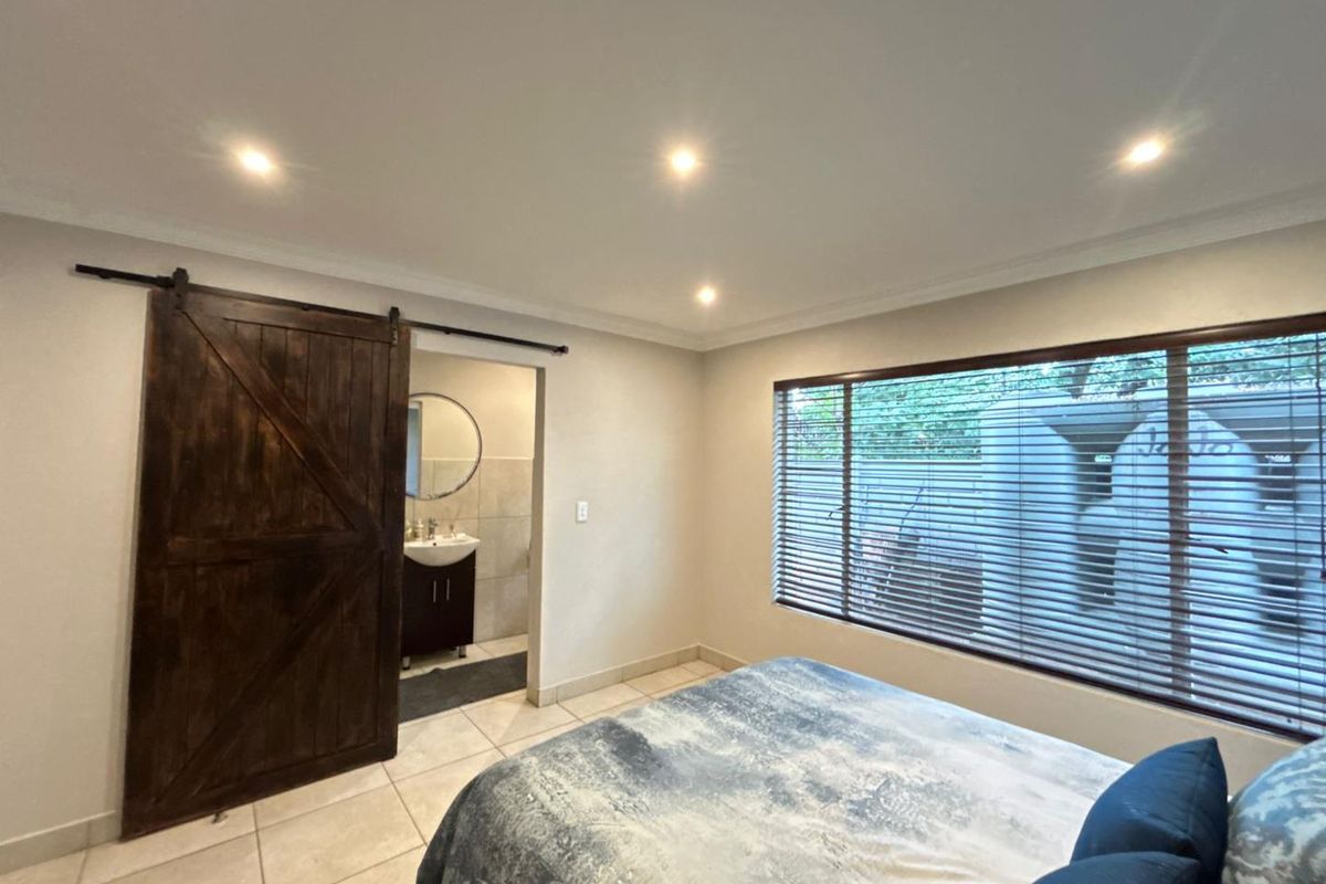 A bedroom featuring tiled flooring, recessed ceiling lighting, and a rustic sliding barn door providing access to an en-suite bathroom.