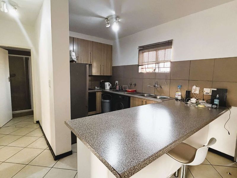 Functional kitchen featuring laminate cabinetry, a breakfast bar, tiled backsplash, and ceramic floor tiles, offering a practical layout for daily use.