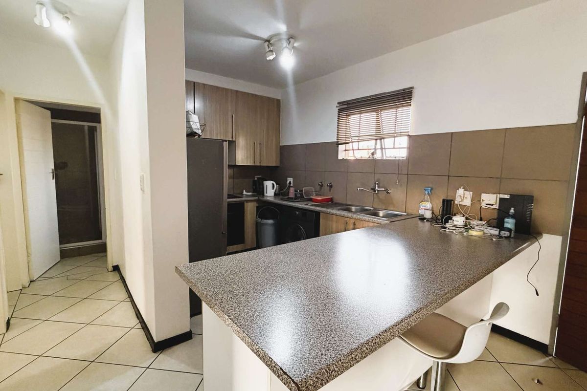 Functional kitchen featuring laminate cabinetry, a breakfast bar, tiled backsplash, and ceramic floor tiles, offering a practical layout for daily use.