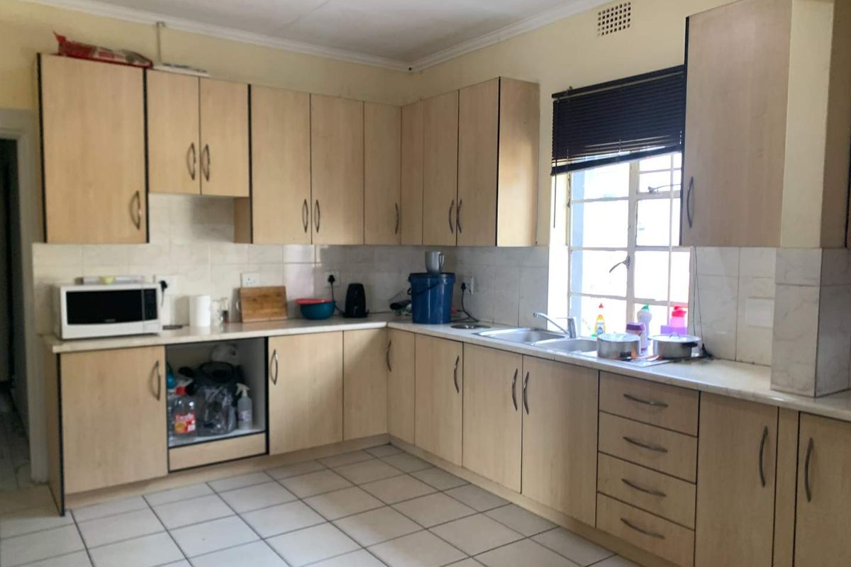 Functional kitchen featuring light wood-finish cabinetry, tiled flooring, double basin sink, and ample counter space for meal preparation.