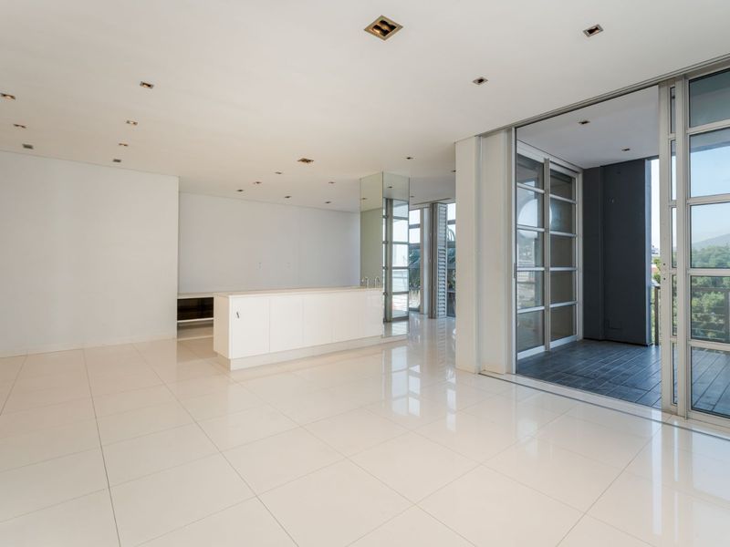 Spacious open-plan living area featuring polished tile flooring, recessed lighting, and large sliding glass doors leading to an outdoor balcony.