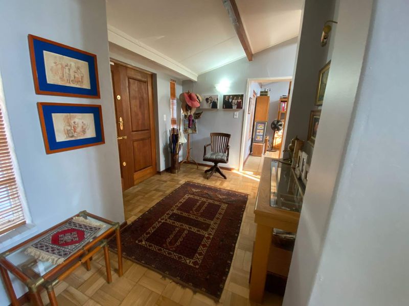 An entrance hall featuring classic parquet flooring, a solid timber front door, and an exposed ceiling beam, leading into the home's interior living spaces.