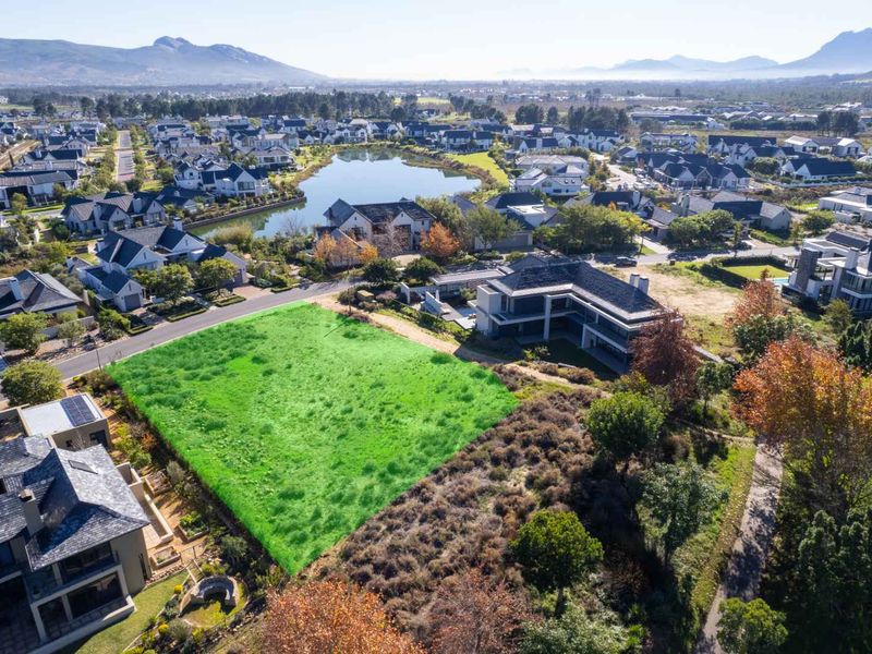 Aerial view of a vacant residential plot situated within a well-established estate, featuring scenic mountain and lake views.