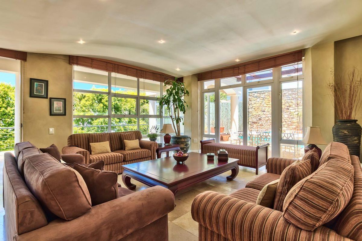 Spacious living room featuring large windows, recessed lighting, and stone tile flooring, with direct access to an outdoor patio area.