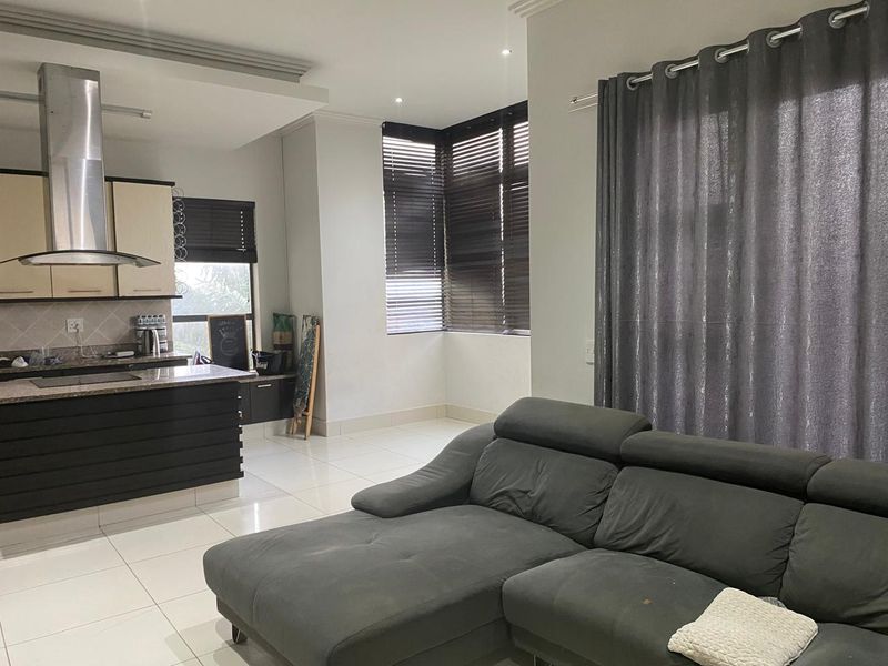 Open-plan living area featuring a modern kitchen with granite countertops, stainless steel extractor fan, and tiled flooring throughout.