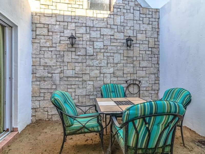 A private outdoor patio area featuring a decorative stone-clad feature wall, wall-mounted lighting, and direct access to the interior via a sliding glass door.