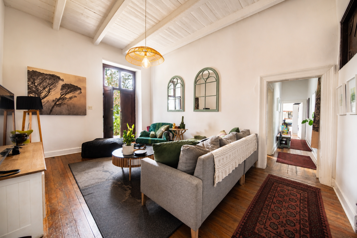 A bright living room featuring exposed timber ceiling beams, original hardwood flooring, and elegant french doors leading to the exterior.