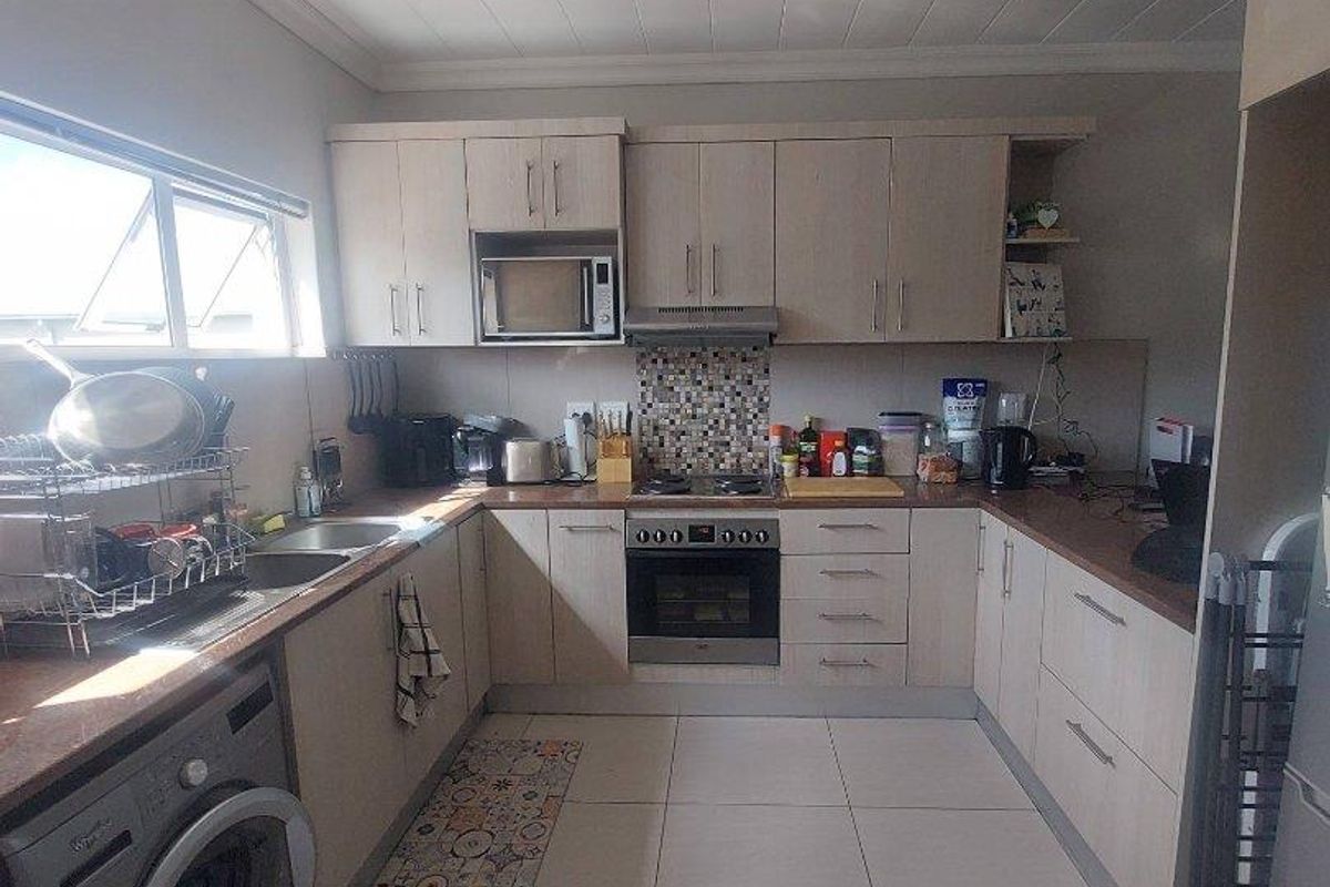 Functional U-shaped kitchen featuring light wood cabinetry, integrated oven and hob, tiled flooring, and a dedicated space for a washing machine.