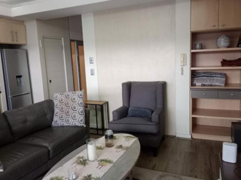 A living room area featuring built-in wooden shelving and laminate flooring, providing a functional and neutral space.