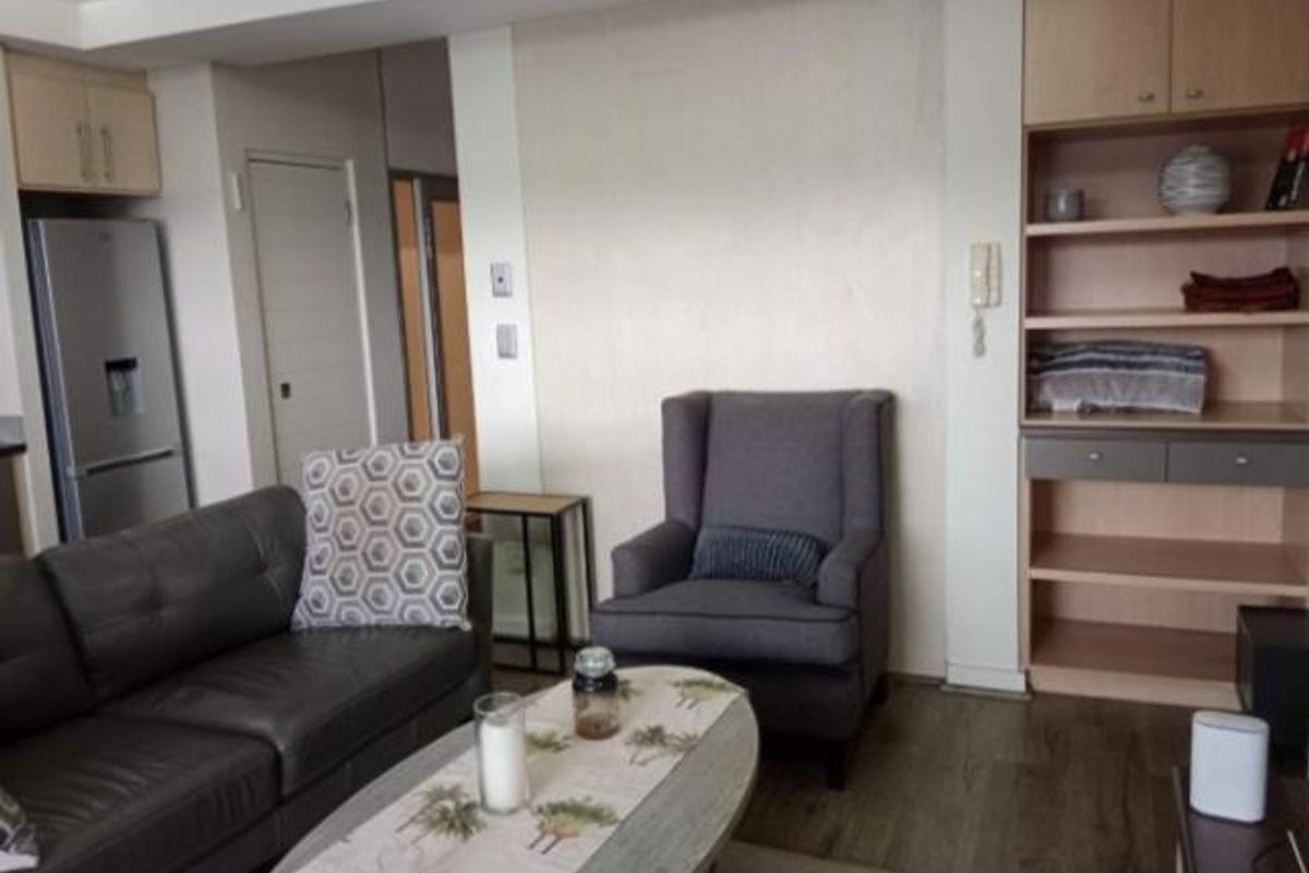 A living room area featuring built-in wooden shelving and laminate flooring, providing a functional and neutral space.