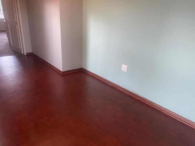An empty bedroom featuring traditional parquet flooring, light-colored walls, and standard electrical fixtures, ready for personalization.