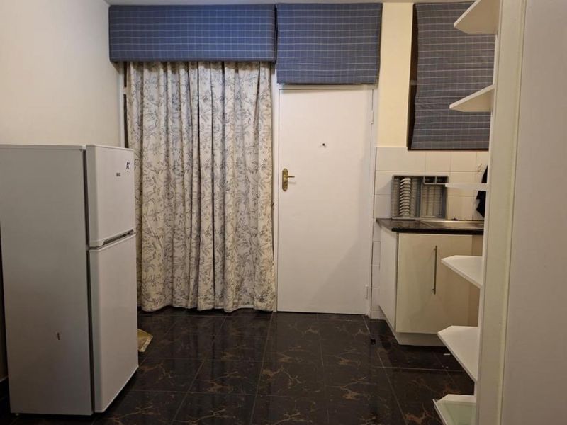 A compact kitchen area featuring dark tiled flooring, built-in cabinetry with granite countertops, and a tiled backsplash.