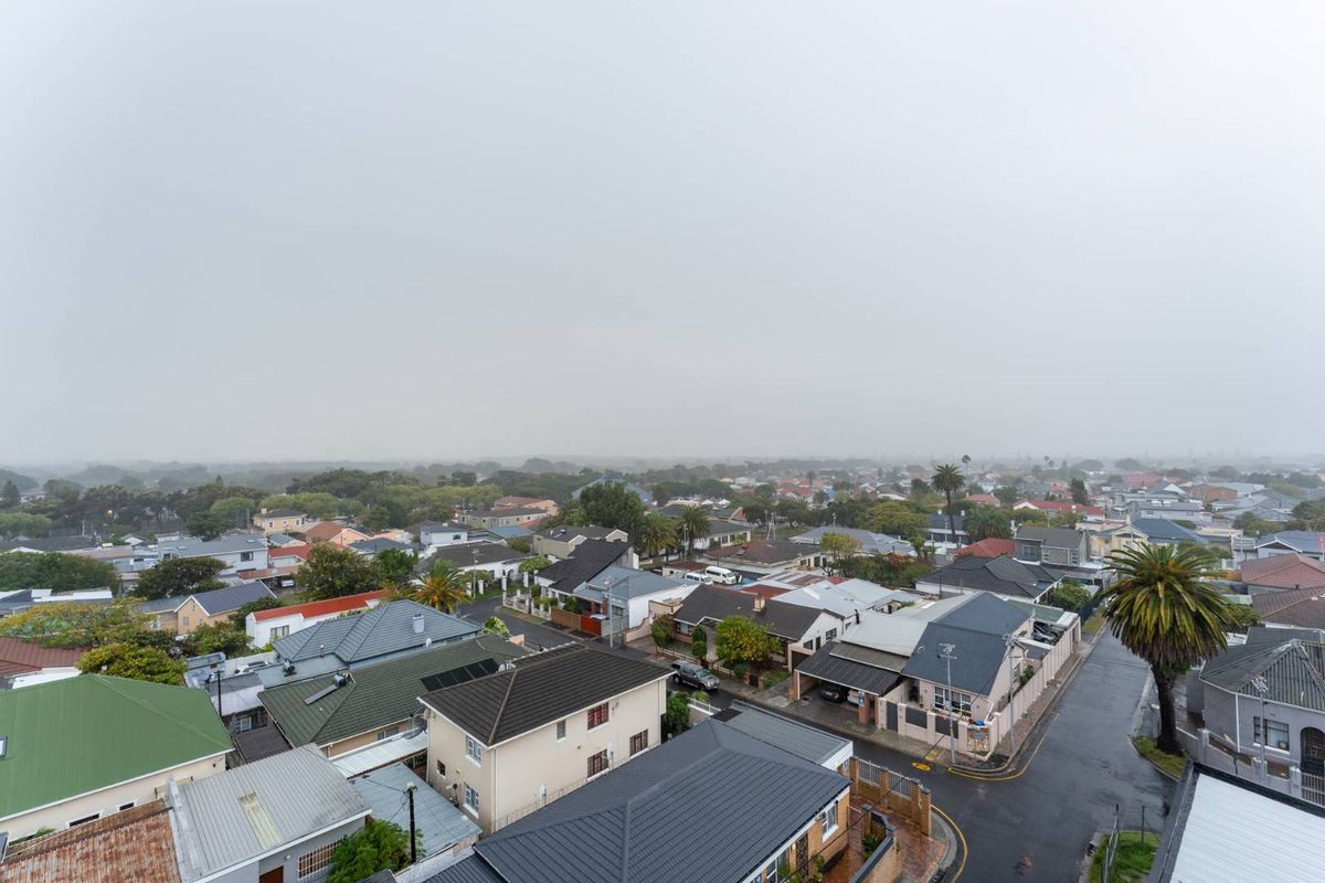 An elevated aerial view overlooking a residential neighborhood with various roof styles and street layouts under an overcast sky.