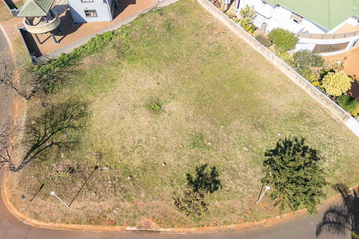 An aerial view of a vacant residential plot situated on a corner, featuring established perimeter walls and street access.