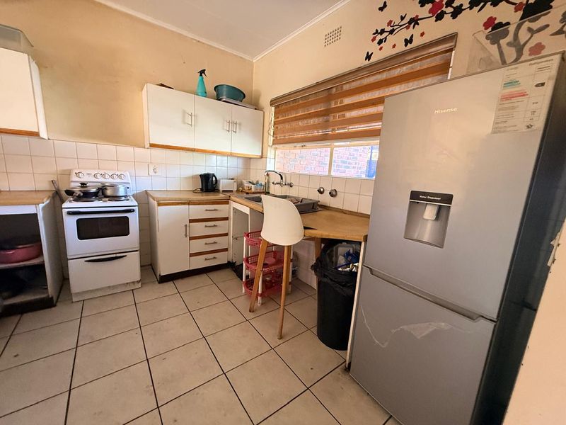 A functional kitchen featuring tiled flooring, a tiled backsplash, built-in cabinetry, laminate countertops, and a freestanding stove.