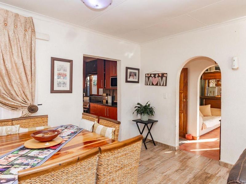 Open plan dining area featuring tiled flooring and an arched doorway leading to adjacent living and kitchen spaces.