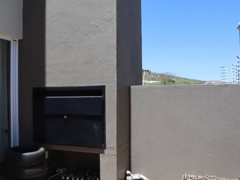 Outdoor patio area featuring a built-in braai and paved flooring, offering a functional space for outdoor entertaining.