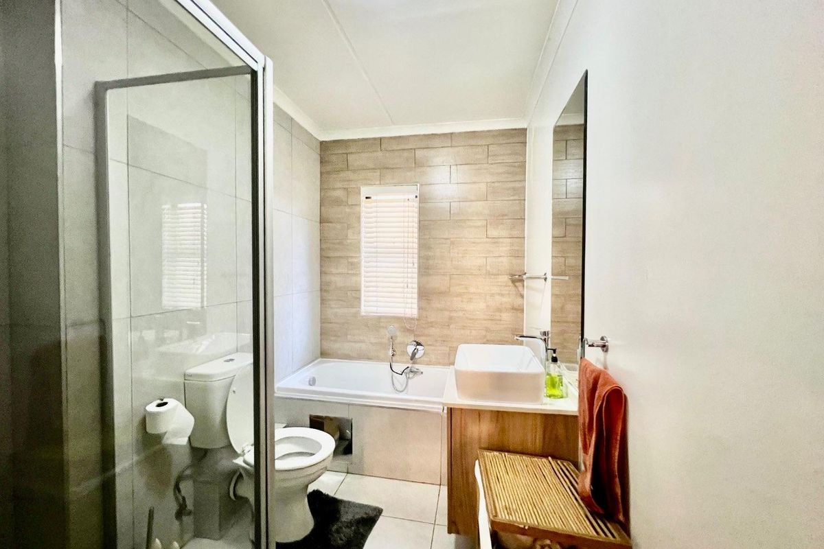 Modern bathroom featuring a glass-enclosed shower, a bathtub with tiled surround, a vessel sink vanity, and neutral wall tiling.