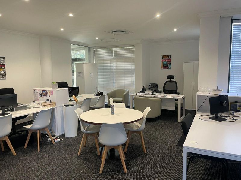 A well-lit, professional open-plan office space featuring neutral finishes, recessed lighting, and integrated storage solutions, suitable for a collaborative work environment.