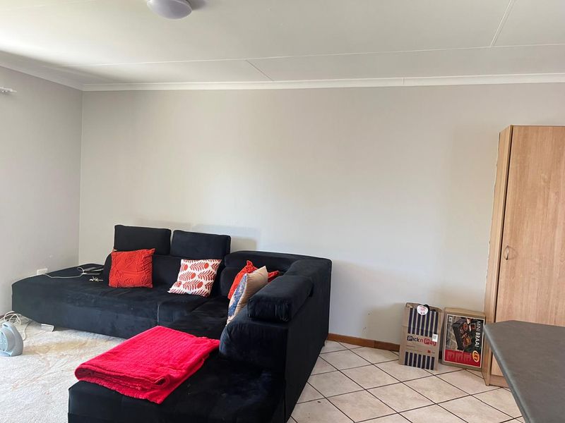 A living room area featuring neutral wall finishes, tiled flooring, and coved ceiling detailing, providing a functional and versatile space.