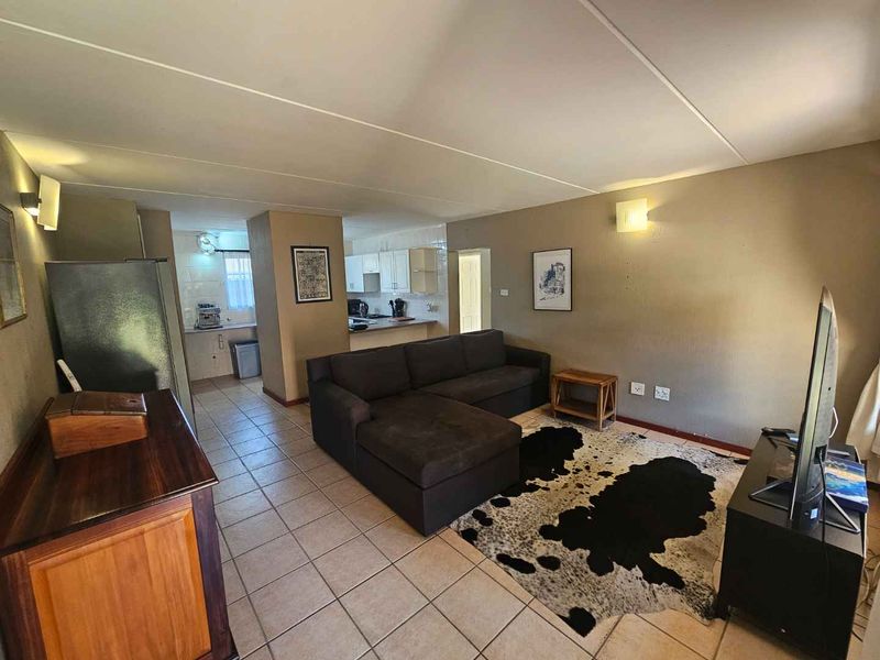 Open plan living area featuring tiled flooring and a connected kitchen space with built-in cabinetry and countertops.