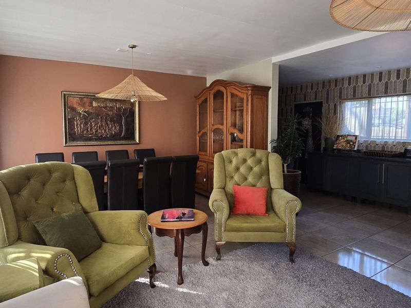 Spacious open-plan living and dining area featuring tiled floors, integrated kitchen appliances, and large sliding doors providing natural light.