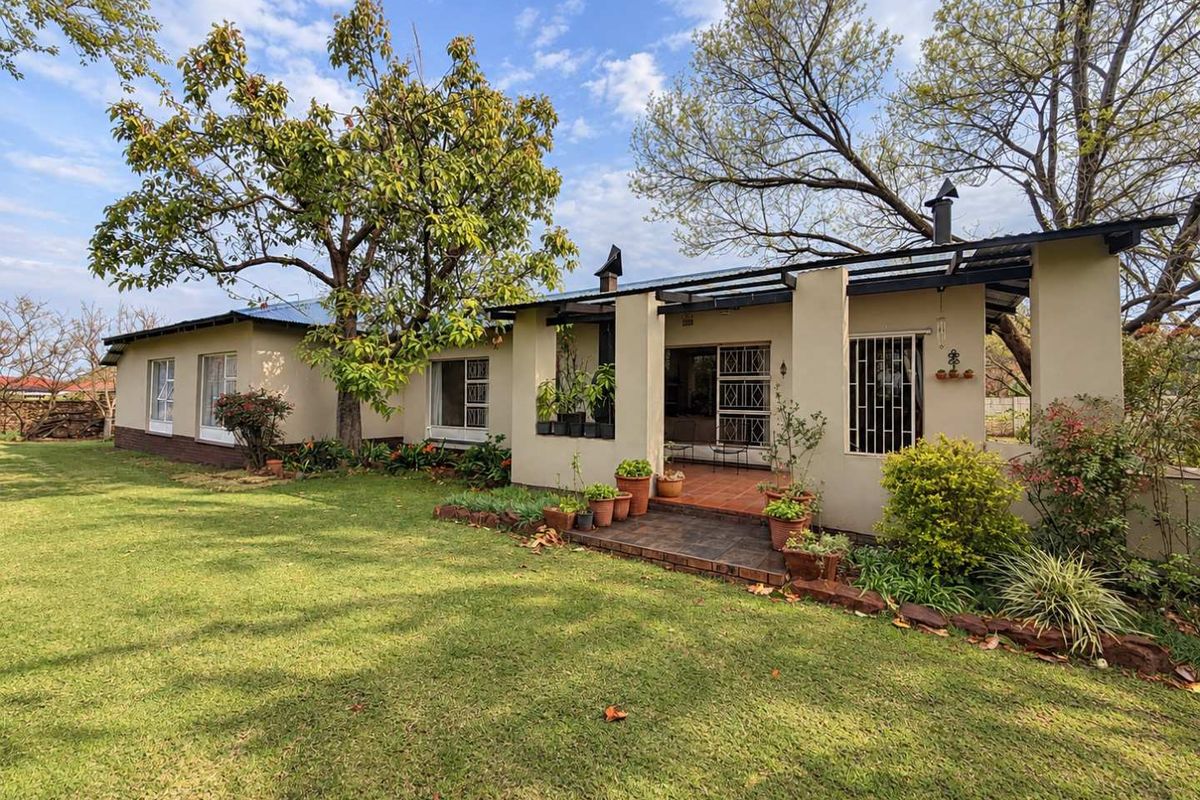 A view of the rear elevation featuring a covered patio, established garden, and secure window treatments.