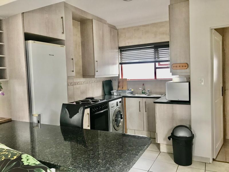 Functional kitchen featuring light wood-finish cabinetry, granite countertops, integrated stove and oven, and tiled flooring with a practical layout.