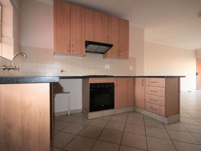 A functional kitchen featuring laminate cabinetry, built-in oven, extractor fan, and tiled flooring, offering a clean and neutral space ready for personalization.