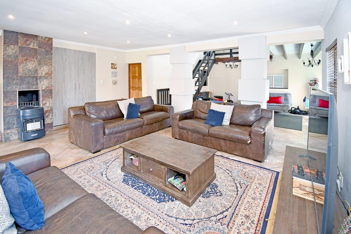 Spacious living room featuring tiled flooring, a freestanding fireplace with stone-look surround, and an open-plan layout leading to a staircase.