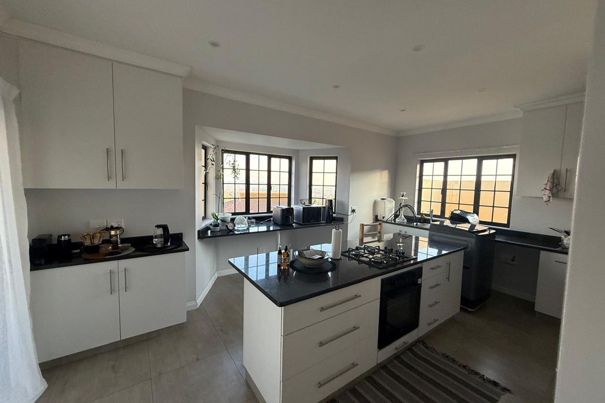 Modern kitchen featuring a central island with a built-in gas hob and oven, granite countertops, and ample white cabinetry.