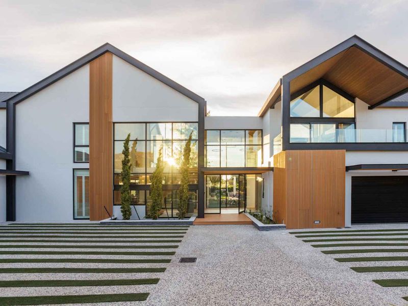 Modern architectural front facade featuring extensive glass glazing, timber cladding, and a clean, contemporary design with a double garage and landscaped driveway.