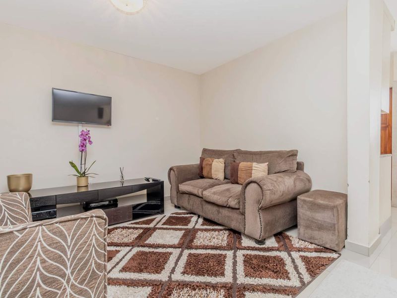 A comfortable living room area featuring neutral wall tones and a wall-mounted television setup.