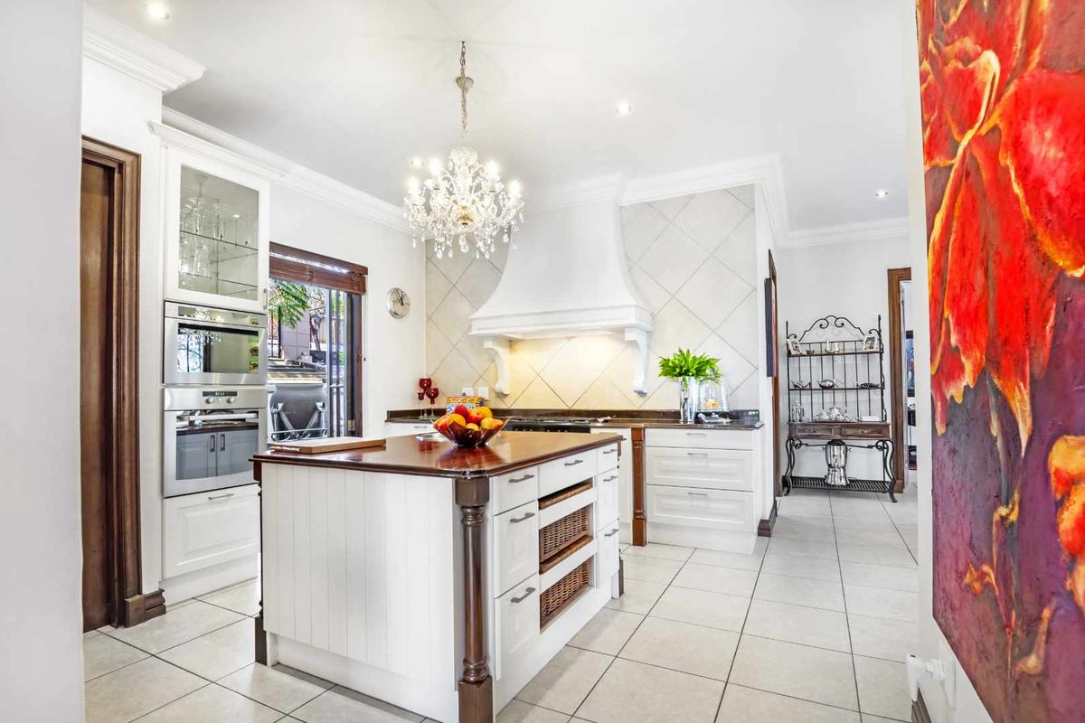 A well-appointed kitchen featuring a central island with a wooden countertop, built-in oven and microwave, and a decorative range hood.