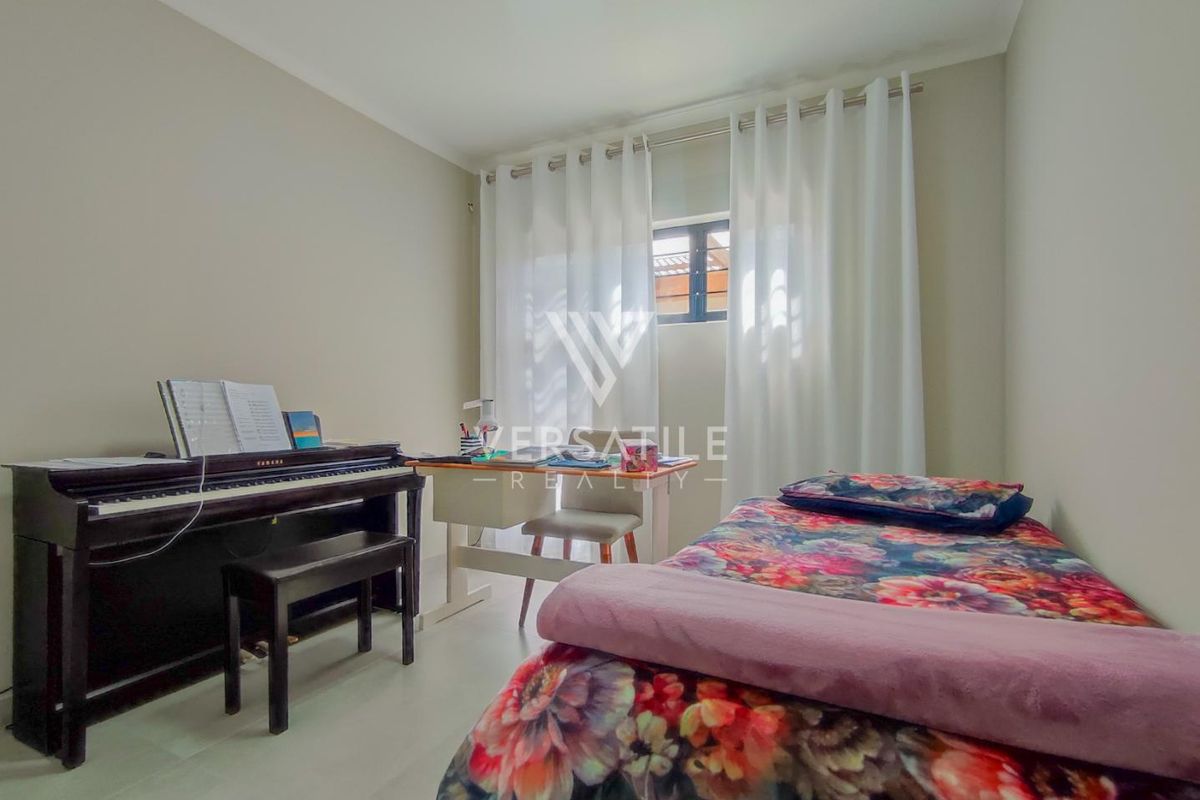 A functional bedroom featuring neutral wall tones, tiled flooring, and a window with fitted curtain rods.