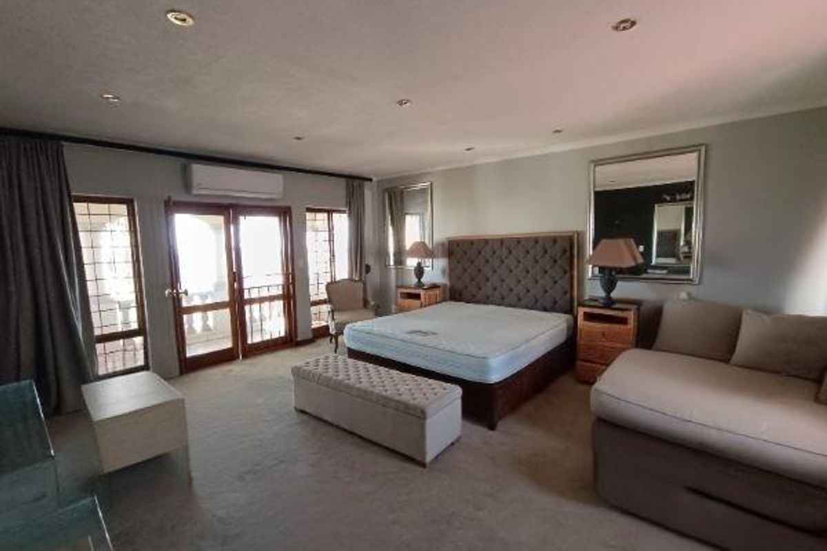 Spacious bedroom featuring recessed lighting, air conditioning, and direct access to an outdoor balcony through double glass doors.