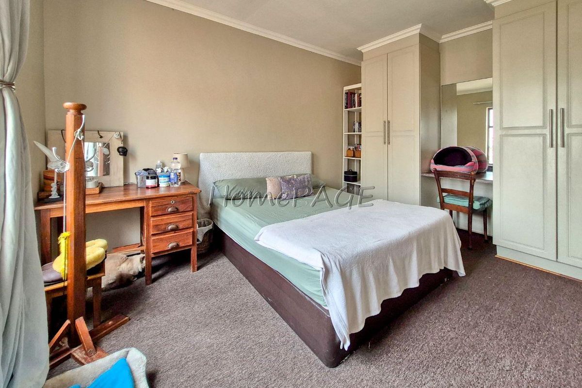 A bedroom featuring built-in cupboards with an integrated vanity area, neutral wall tones, and carpeted flooring.
