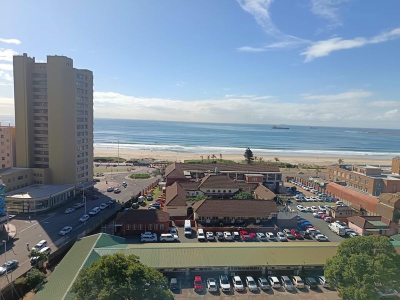 Elevated coastal view overlooking the beach, ocean, and surrounding urban infrastructure.